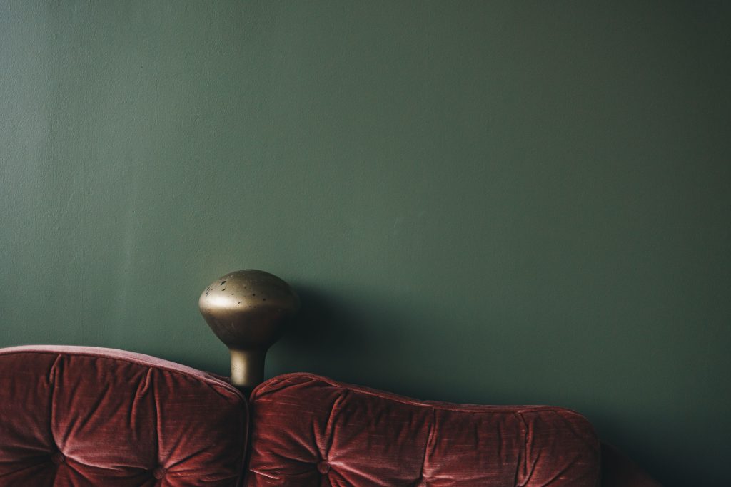 Fluwelen bank tegen een diepgroene accentmuur in de woonkamer