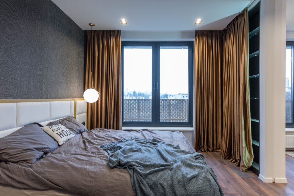 Slaapkamer met bed, lamp en gordijnen voor het raam