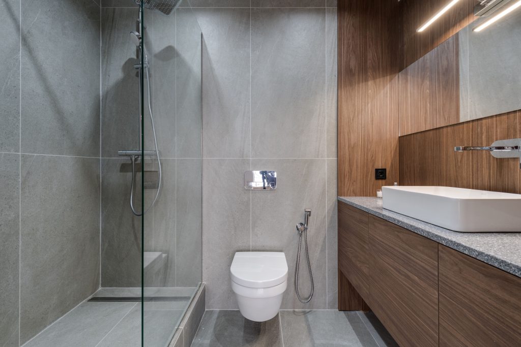 Moderne kleine badkamer met inloopdouche, wastafel en toilet in houtlook