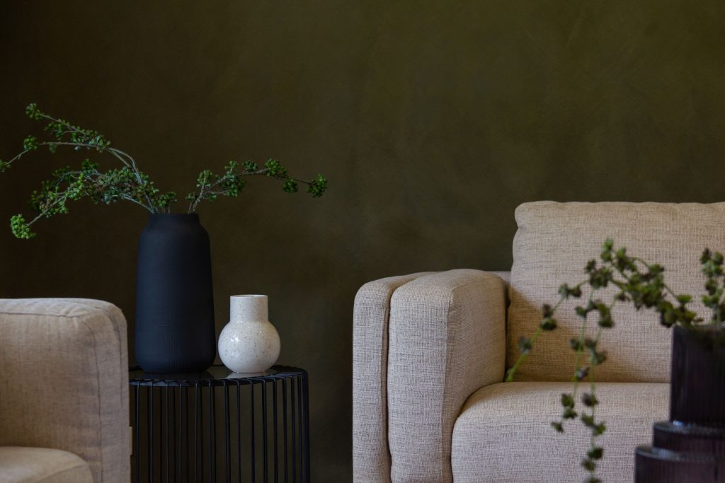 Minimalistische woonkamer met donkergroene muren en neutrale tinten