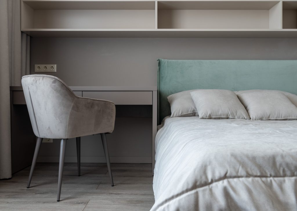 Lichte slaapkamer met bed en een tafel met stoel onder wandplanken